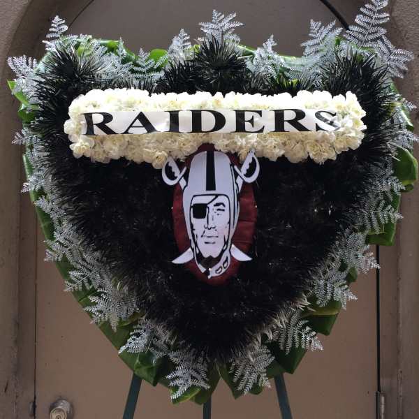 Heart-shaped funeral wreath with white flowers and a Raiders emblem