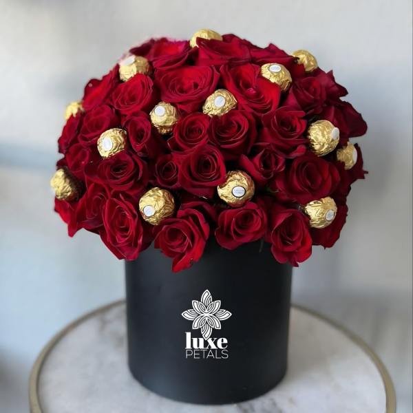 Red roses and gold-wrapped chocolates in a black box