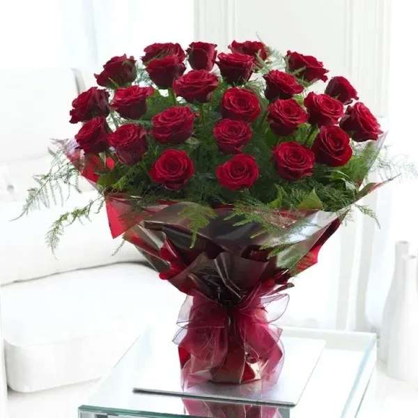Bouquet of red roses wrapped in burgundy paper with a ribbon