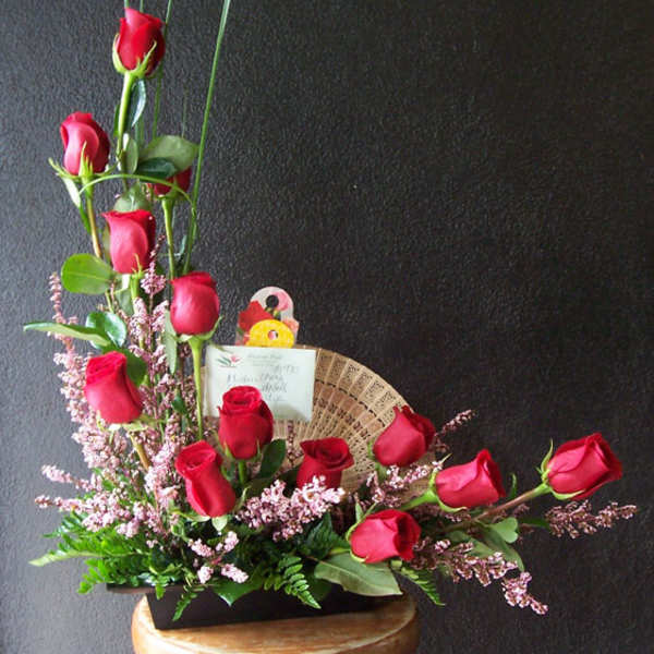 Red roses arranged in a low black container with pink filler flowers