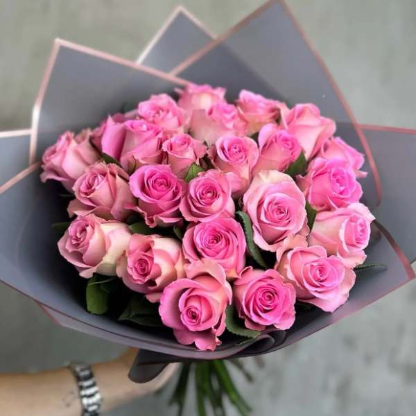 Bouquet of pink roses wrapped in dark paper