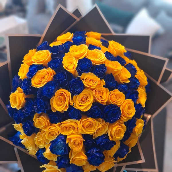 Bouquet of yellow and blue roses wrapped in black paper