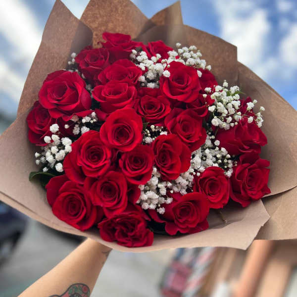 Bouquet of red roses with white baby's breath in brown paper