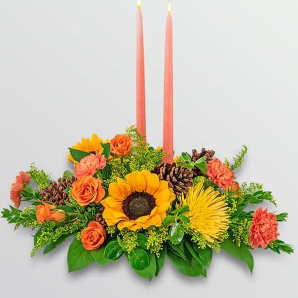 Floral centerpiece with two pink taper candles and autumn-colored blooms