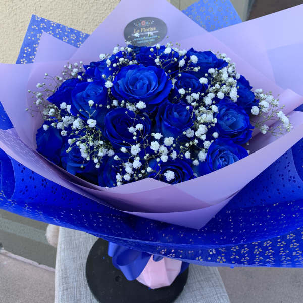 Bouquet of vivid blue roses with white baby's breath in lavender and blue wrap