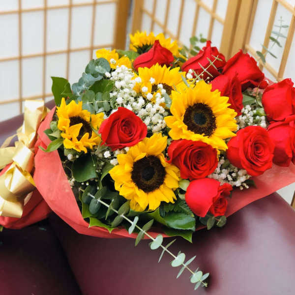 Bouquet of red roses and yellow sunflowers wrapped in pink paper
