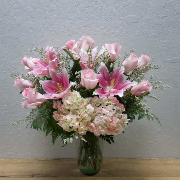 Pink lilies and roses arranged in a glass vase