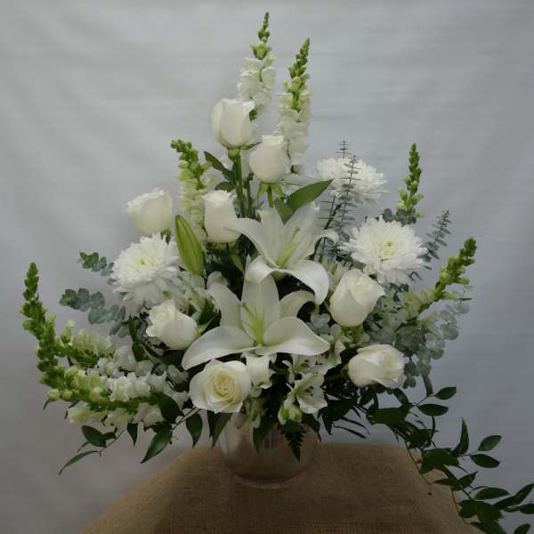 White floral arrangement with roses, lilies, and chrysanthemums in a vase