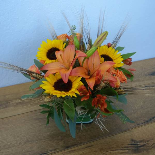 Orange lilies and yellow sunflowers in a low vase arrangement