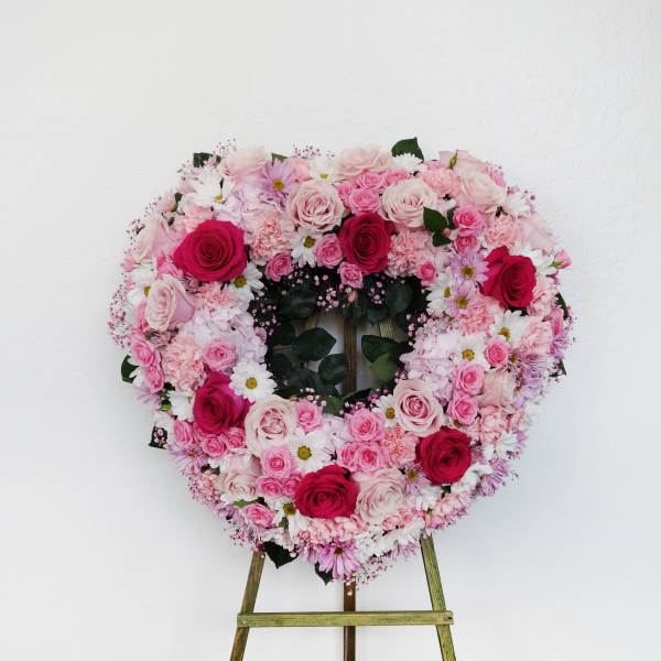 Heart-shaped floral wreath on an easel with pink and white roses