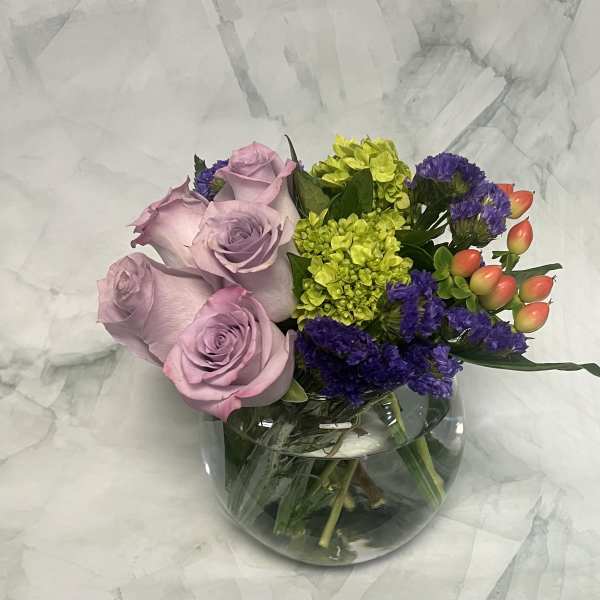 Lavender roses with purple and lime-green flowers in a glass vase