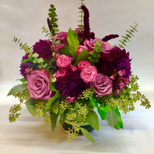 Bouquet of pink and purple roses with greenery in a vase