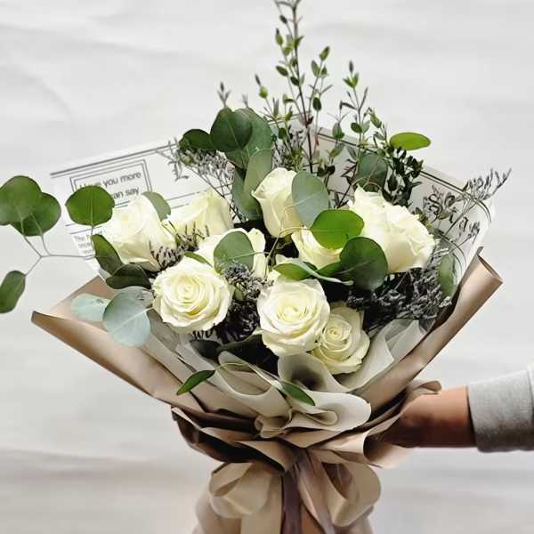 Bouquet of white roses with eucalyptus in tan wrapping