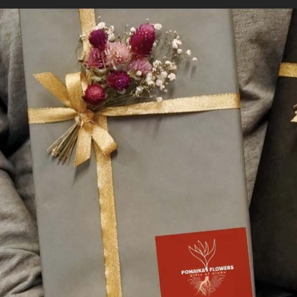 Two wrapped gift boxes with small dried flower accents and gold ribbon