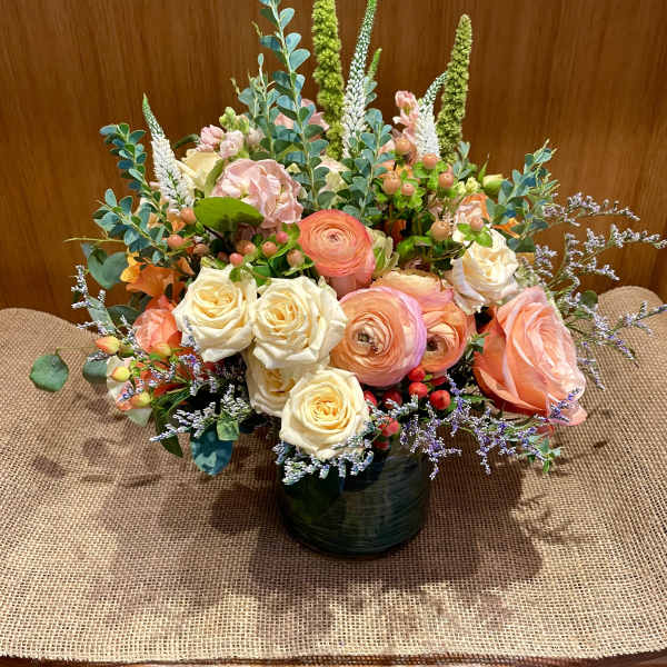 Mixed bouquet of peach and cream roses in a dark vase