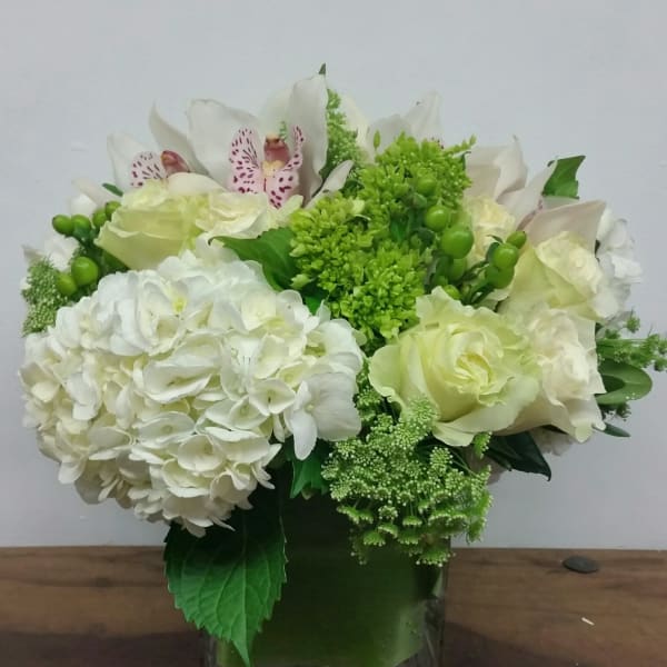 White and green floral arrangement in a square glass vase