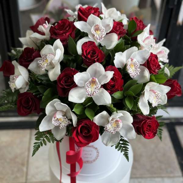Bouquet of red roses and white orchids in a white hat box with a red ribbon