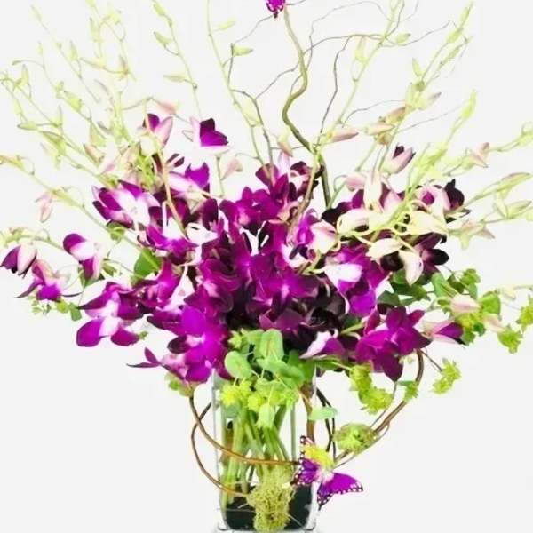 Purple orchids in a glass vase with butterfly accents