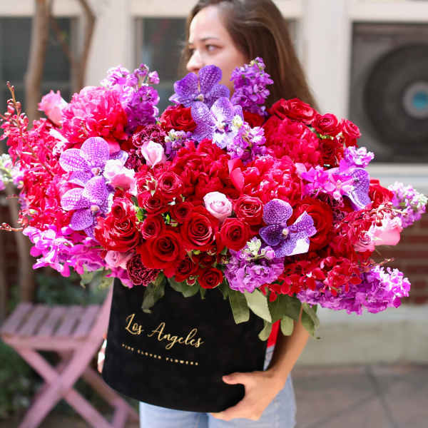 Large bouquet of red roses and purple orchids in a black box