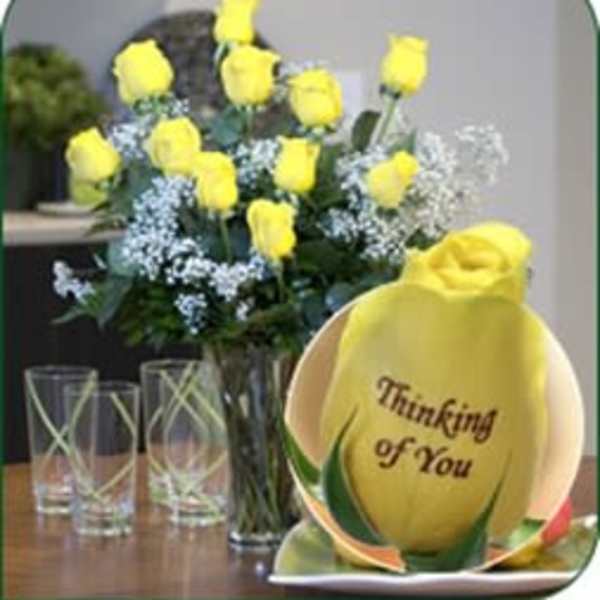 Yellow roses in a glass vase beside a yellow "Thinking of You" gift