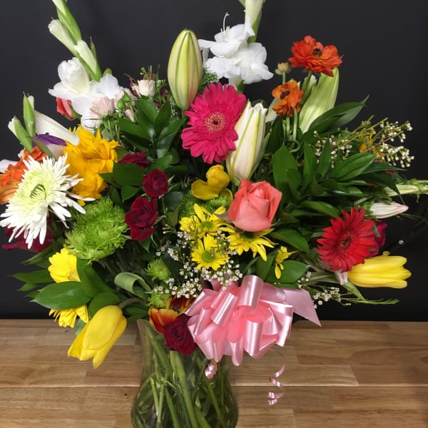 Colorful mixed bouquet in a glass vase with a pink ribbon
