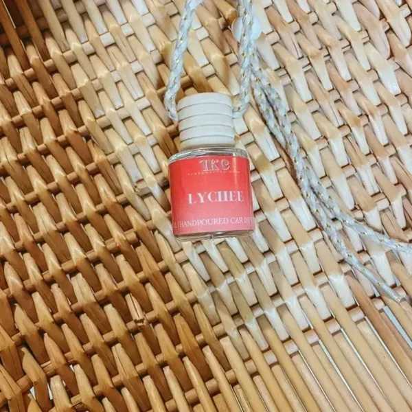 Small lychee-scented hanging candle bottle on a woven surface