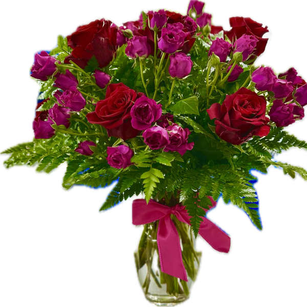 Red roses and pink spray roses in a glass vase with a ribbon