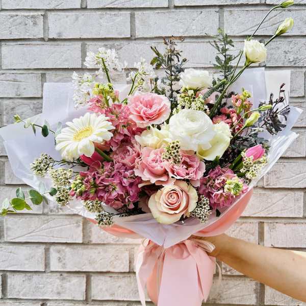 Pink and white mixed bouquet with roses and gerbera daisies wrapped in pink paper