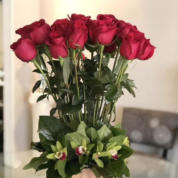 Tall arrangement of red roses with green orchids in a wooden box