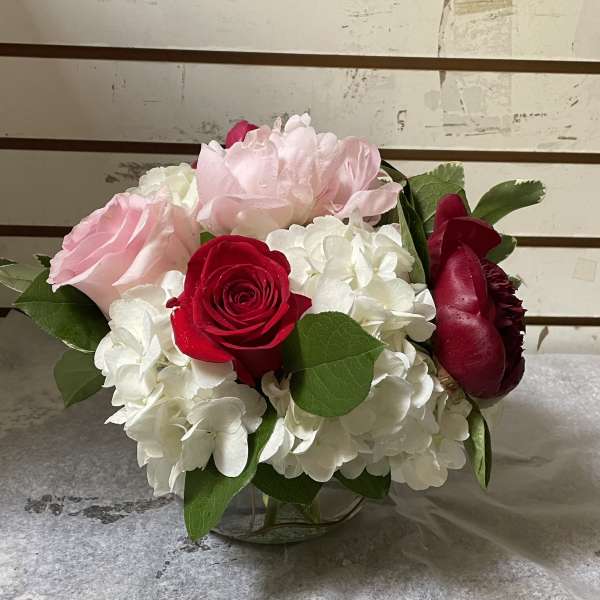 Pink and red roses with white hydrangeas in a glass vase
