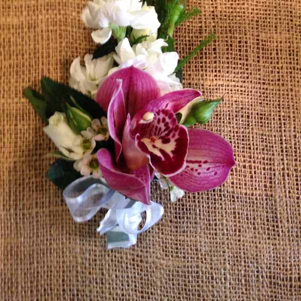 Pink orchid corsage with white flowers and a silver ribbon