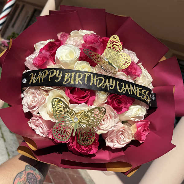 Pink and white rose bouquet with a birthday ribbon and butterfly decorations