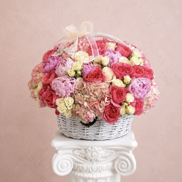 Basket of pink and cream roses with hydrangeas and a ribbon bow