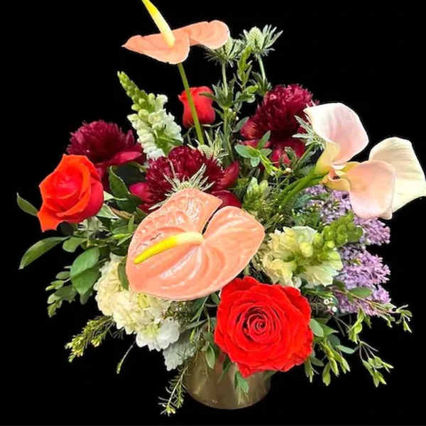 Mixed bouquet with red roses and peach calla lilies in a vase