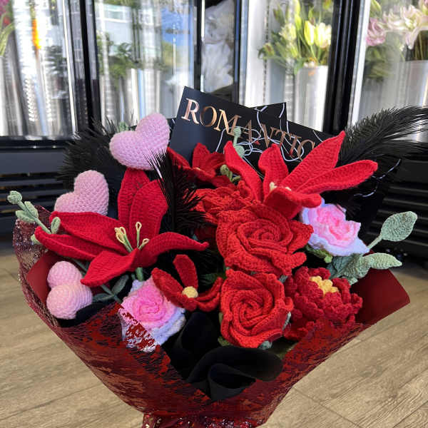 Crocheted red and pink flower bouquet with heart accents and black feathers