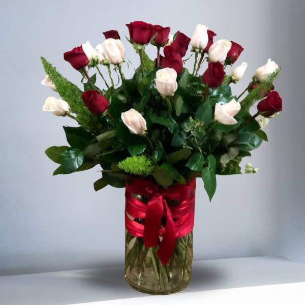 Tall glass vase of red and white roses wrapped with a red ribbon bow