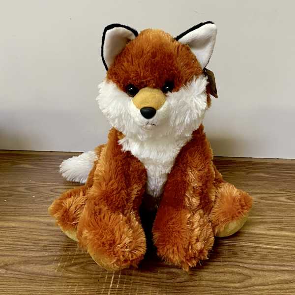 Plush fox toy sitting on a wooden floor