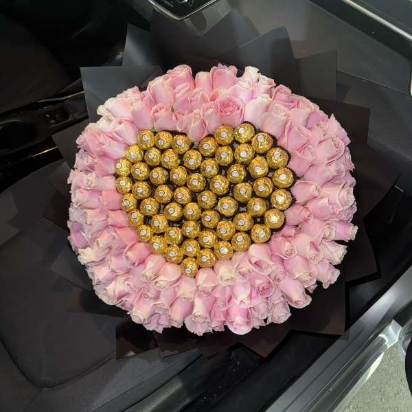 Heart-shaped bouquet of pink roses with gold-wrapped chocolates in the center