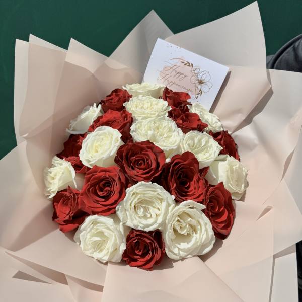 Bouquet of red and white roses wrapped in pale pink paper