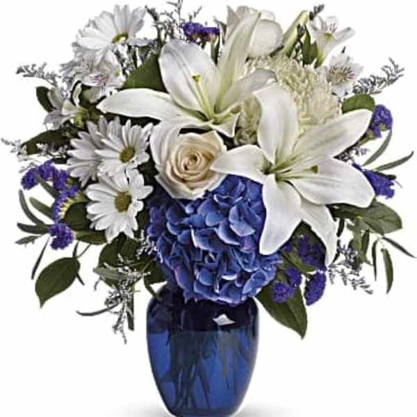White lilies and daisies with blue hydrangea in a blue vase