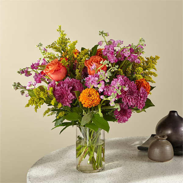 Mixed bouquet of pink, orange, and purple flowers in a clear glass vase