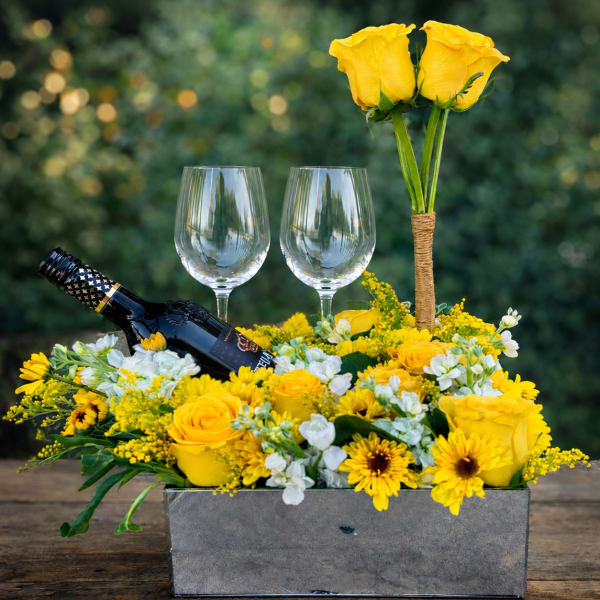 Yellow rose centerpiece with wine bottle and two glasses in a rectangular box