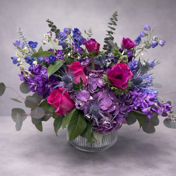 Purple and pink floral arrangement in a clear glass vase