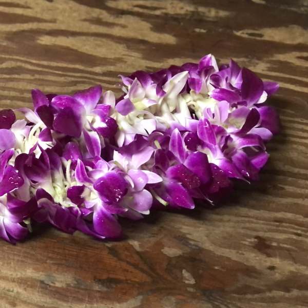 Purple orchid lei on a wooden surface