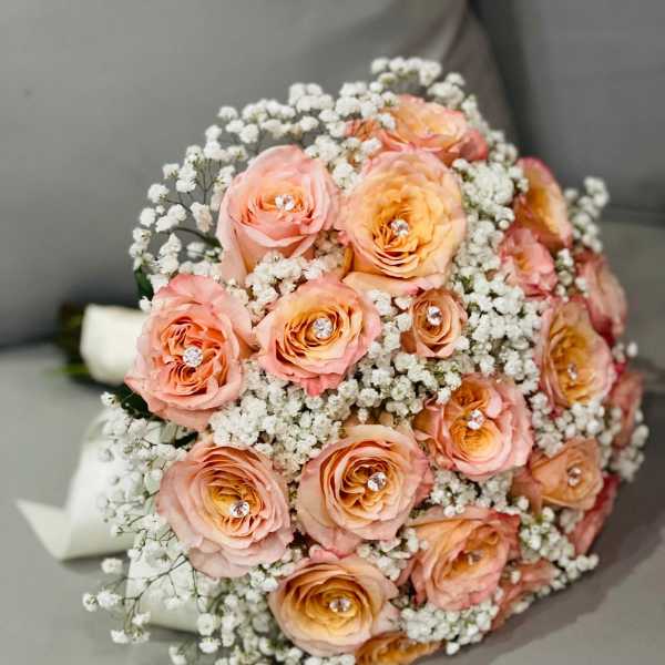 Peach roses with baby's breath in a rounded bouquet