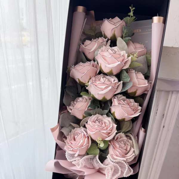 Bouquet of pale pink roses in a black gift box with ribbon