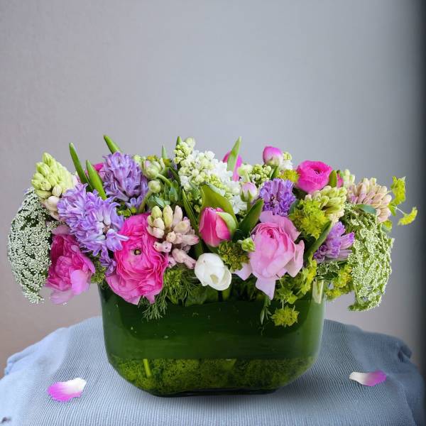 Pink and purple mixed flower arrangement in a green glass vase