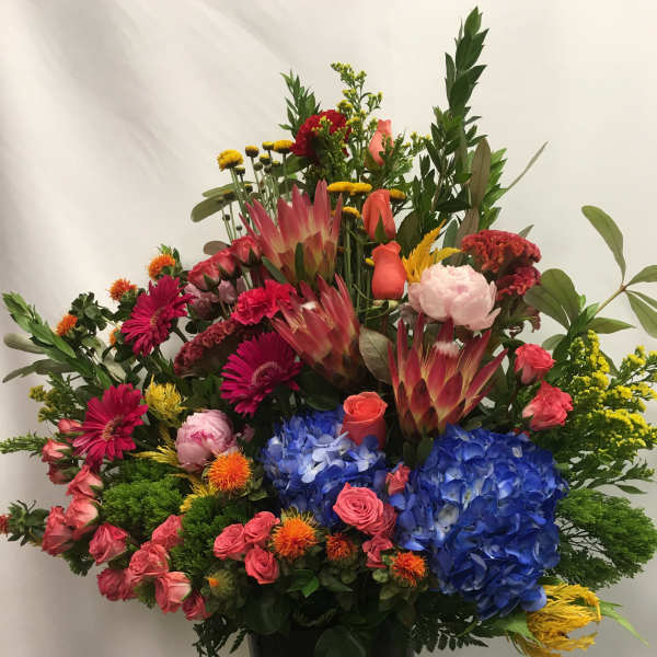 Large mixed bouquet in a black vase with blue hydrangeas and pink roses