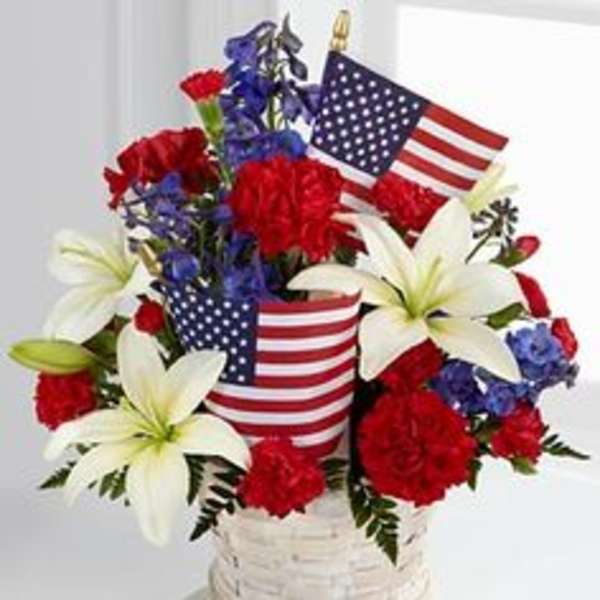 Red, white, and blue floral arrangement in a white basket with American flags