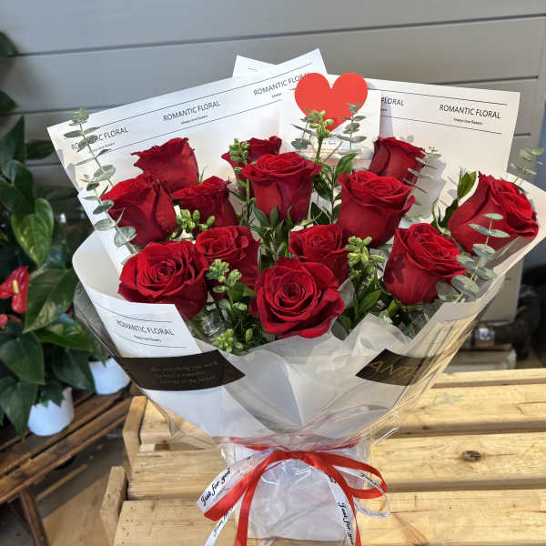 Bouquet of red roses wrapped in white paper with a red ribbon